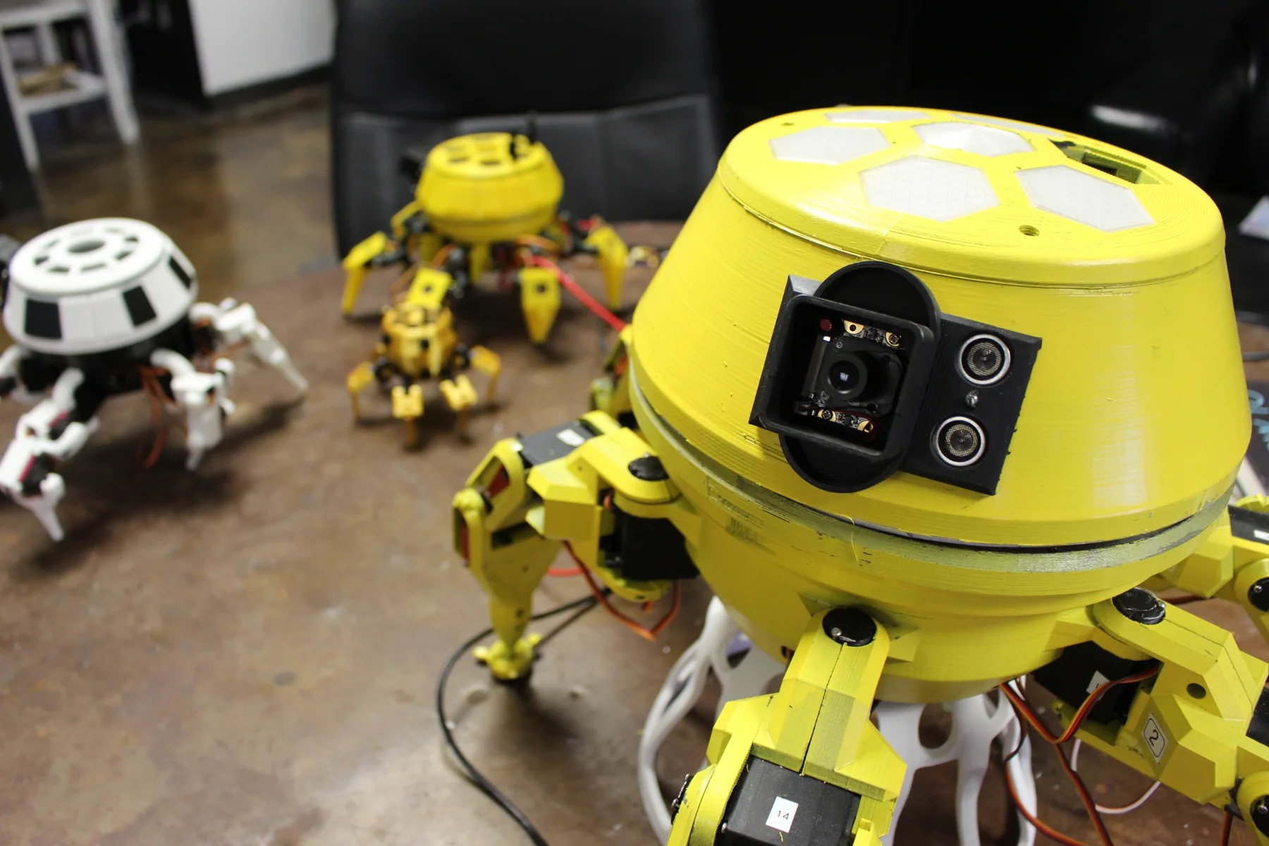 Yellow Skuttlebot robot with camera and sensor array on a workshop bench